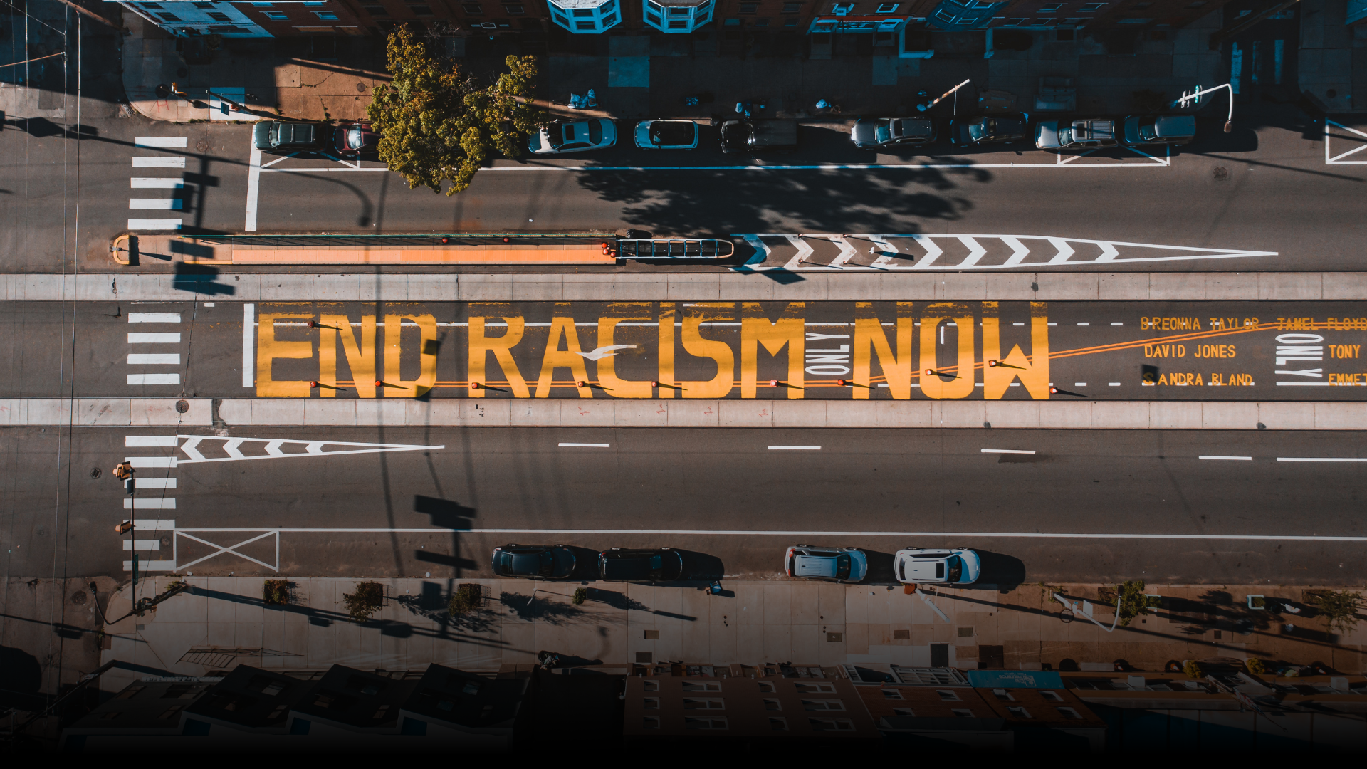 City roadway with END RACISM NOW text on ground